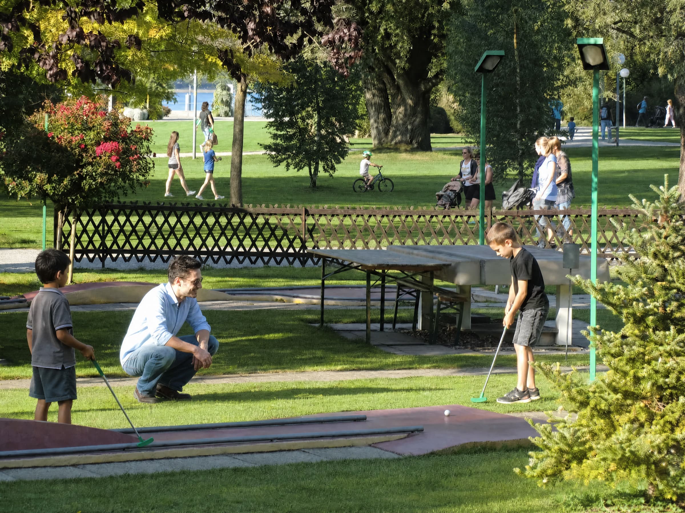 Kinder spielen Minigolf, Vater schaut zu — Pan Rolito Anlage im Sommer.
